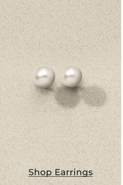 Pair of pearl stud earrings on textured background. Click to Shop Earrings