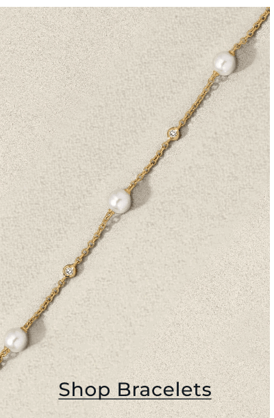 Gold bracelet with pearl and diamond accents on textured background. Click to Shop Bracelets