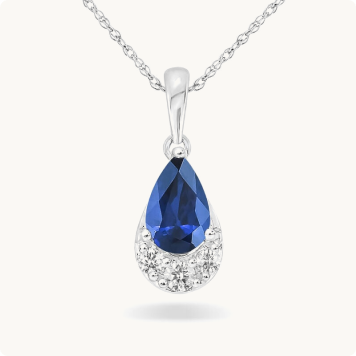 Pear-Shaped Sapphire & Diamond Drop Pendant in 10k White Gold: Pear-shaped blue sapphire pendant necklace with a small diamond accent cluster at the base, set in white gold on a delicate chain.