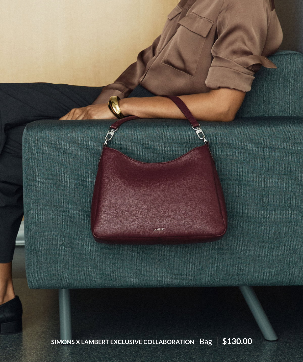 Simons x Lambert Exclusive Collaboration. Bag 130$. The photo shows a woman carrying the Hannah minimalist trapeze bag in burgundy.