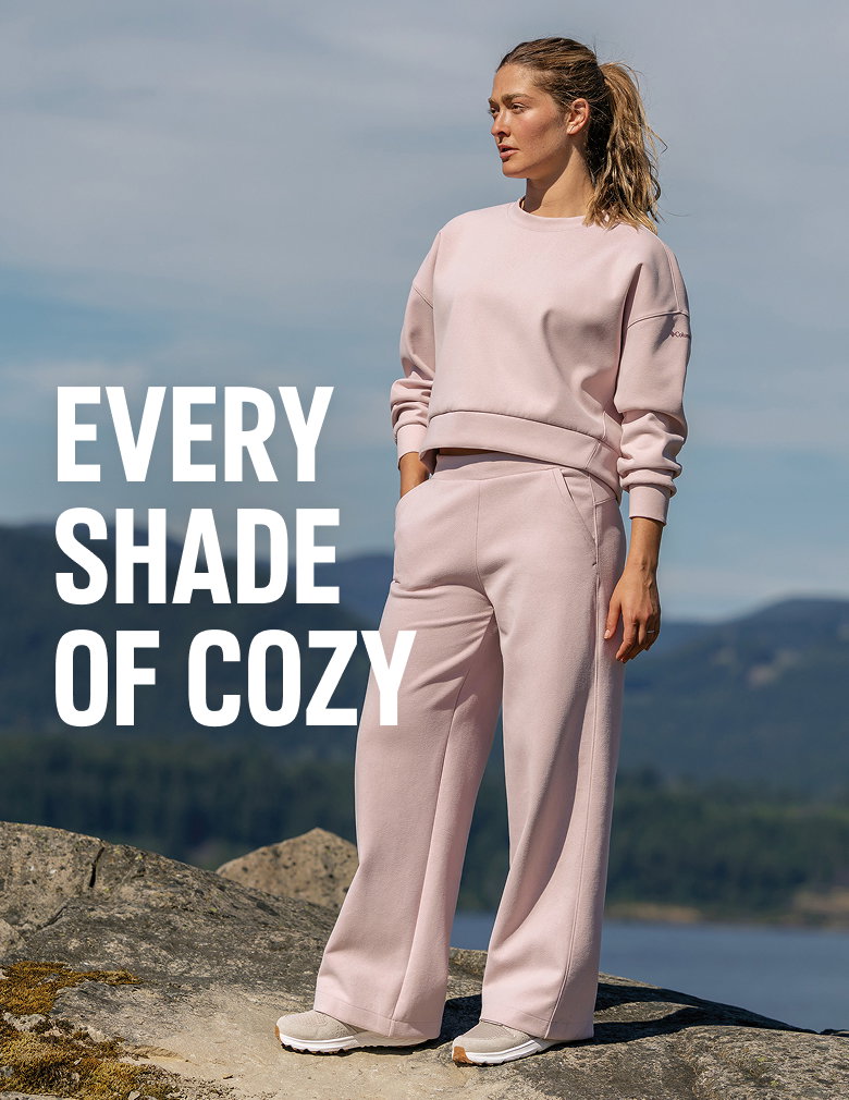 A woman wearing a light pink sweat set, standing outside with text: EVERY SHADE OF COZY