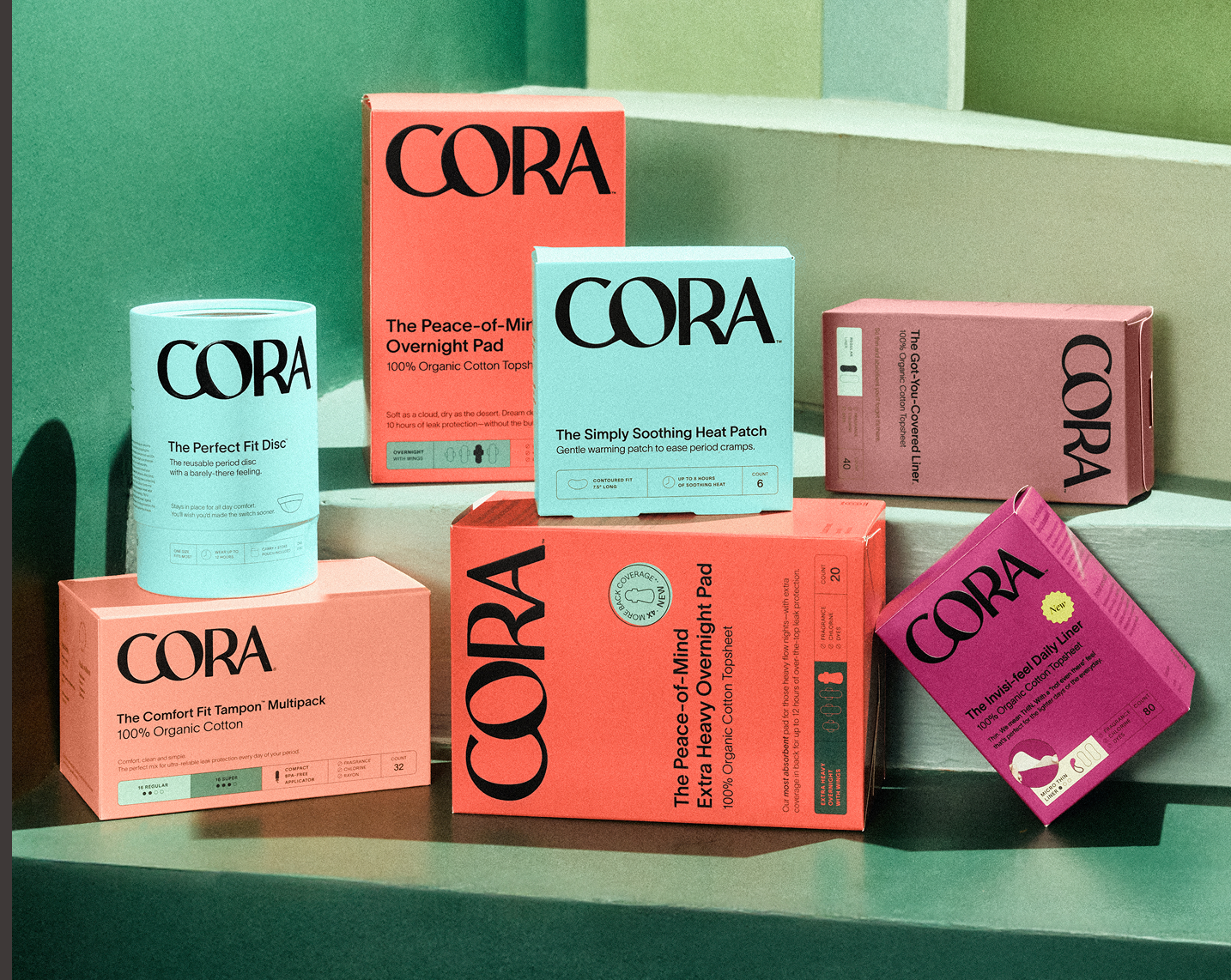 Assortment of Cora period product boxes on green steps