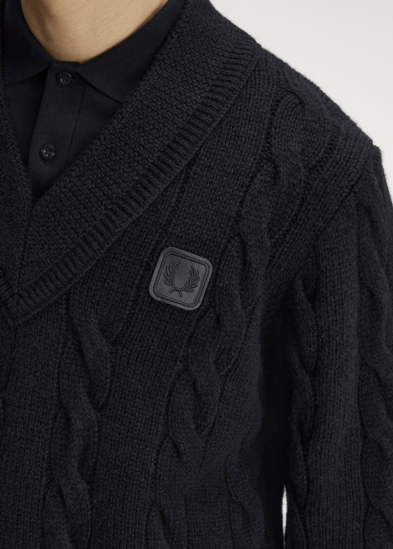 Close up of a Fred Perry Leather Patch Cable Knit Jumper in Black