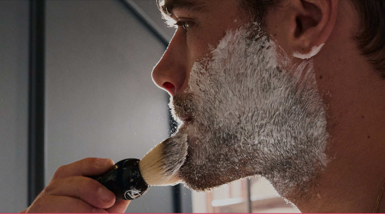 Lifestyle image of shaving cream being applied with a shaving brush.