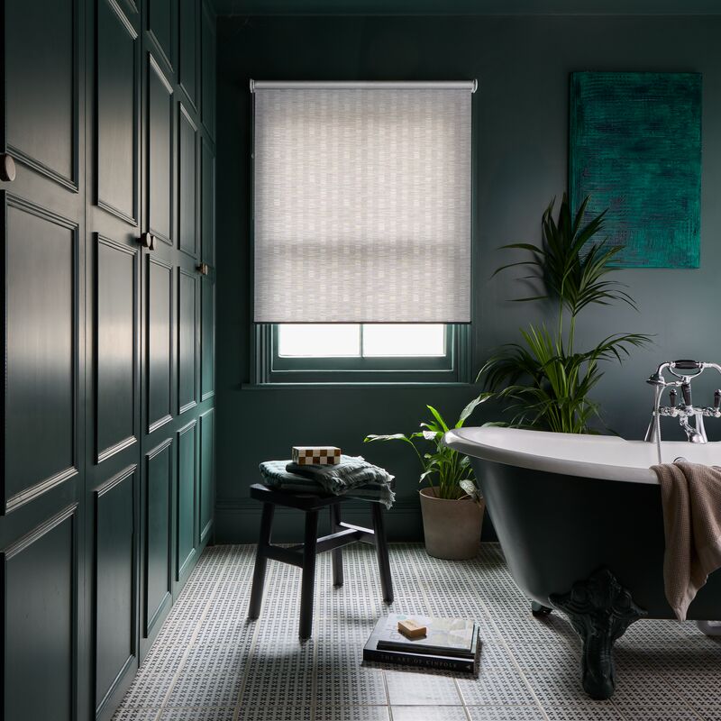 Light-filtering Roller blind at a recessed bathroom window, complementing dark panelled walls, indoor plants and a freestanding bath.