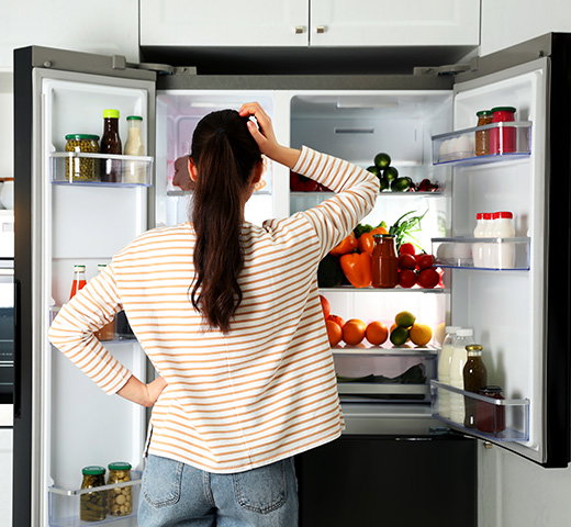 A homeowner scratching their head in front of an open fridge