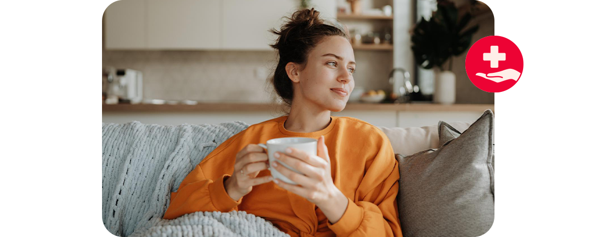Frau sitzt entspannt mit einer Tasse auf dem Sofa.