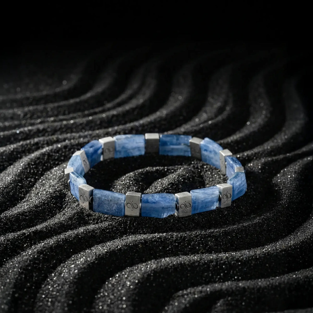 Kyanite Bracelet VIII, with rectangular 8mm blue stones and silver accents, on black sand.