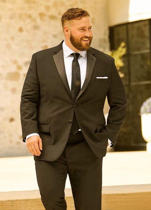 A man with a beard dressed in a classic black tuxedo for a formal event.