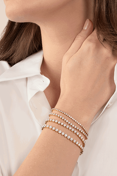 Model wearing layered tennis bracelets.
