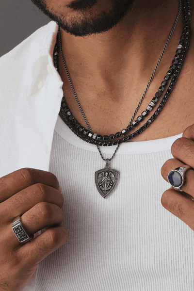 Model wearing layered men’s necklaces.