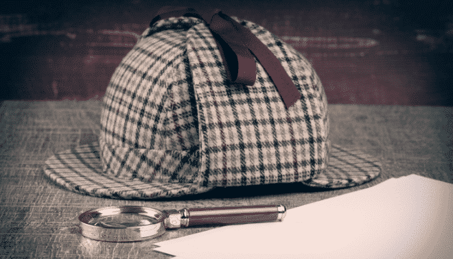 A deerstalker hat and a magnifying glass rest on a table beside several sheets of paper.