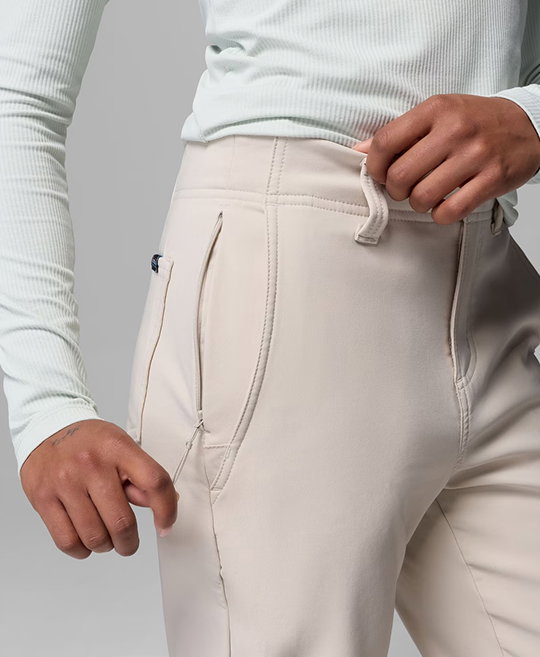 A model unzipping the hidden pocket of their white pair of pants.