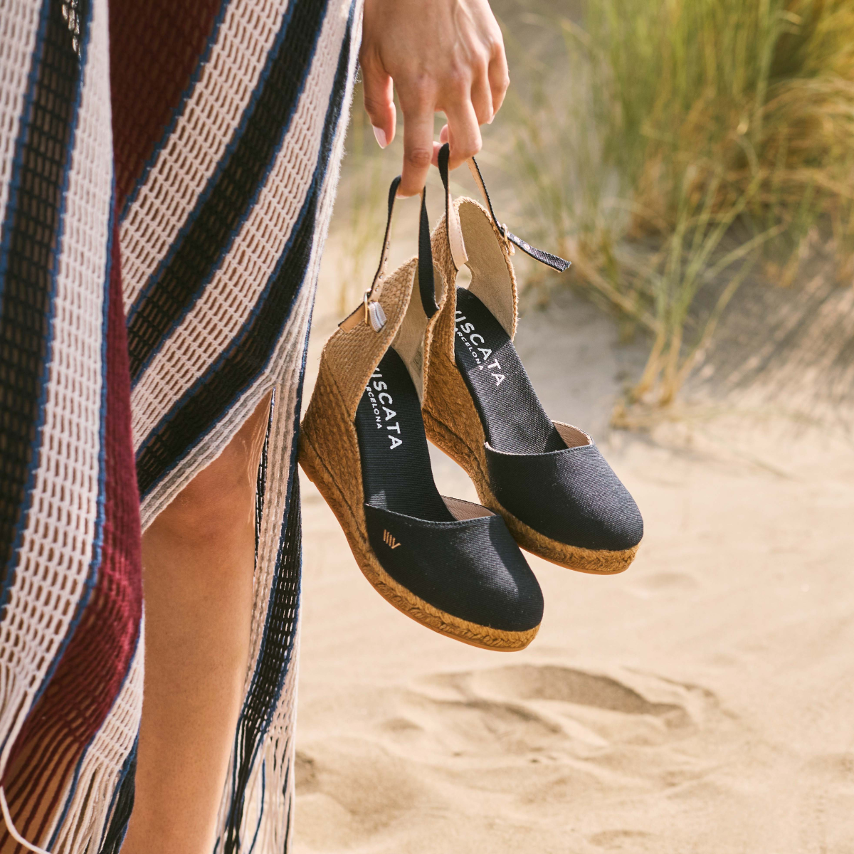 Woman holding a Viscata shoe box, wearing a relaxed outfit against a clean neutral background.