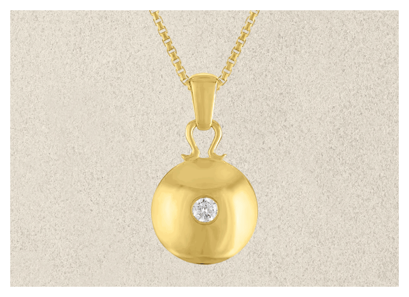 Gold pendant chain with diamond in center against textured background.
