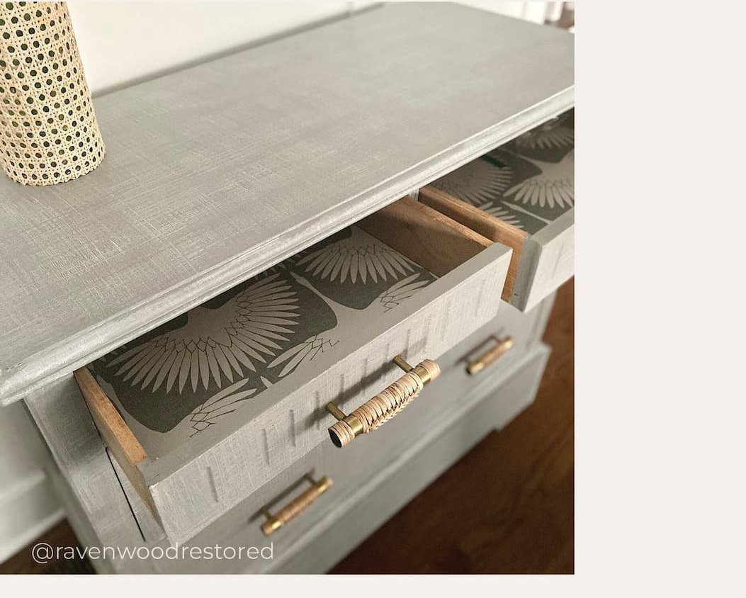 Image of a light colored dresser with Tempaper's Feather Flock installed inside the drawers"
