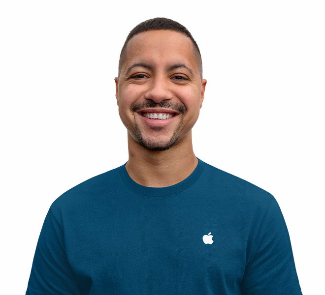 An Apple Specialist, dressed in a dark blue shirt with an Apple logo, smile on his face