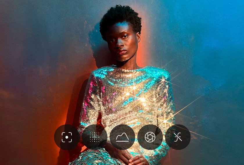Demonstration of Pro controls UI menu, Camera app, controls for lens aperture, shutter speed, white balance, and histogram displayed, overlaid on a picture of person wearing a sparkly metallic dress against a colorful backdrop