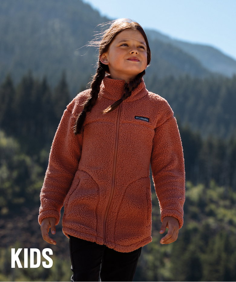 A child in a forested setting wearing a Fleece zip up. 