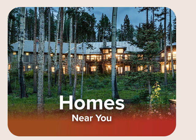 Forest lodge glowing in the evening among tall trees and wildflowers.