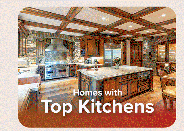 Luxury kitchen with wood cabinetry, stone accents, large island, and coffered ceiling.