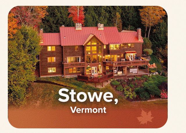 Large mountain lodge surrounded by colorful fall flora and rolling forested hills.