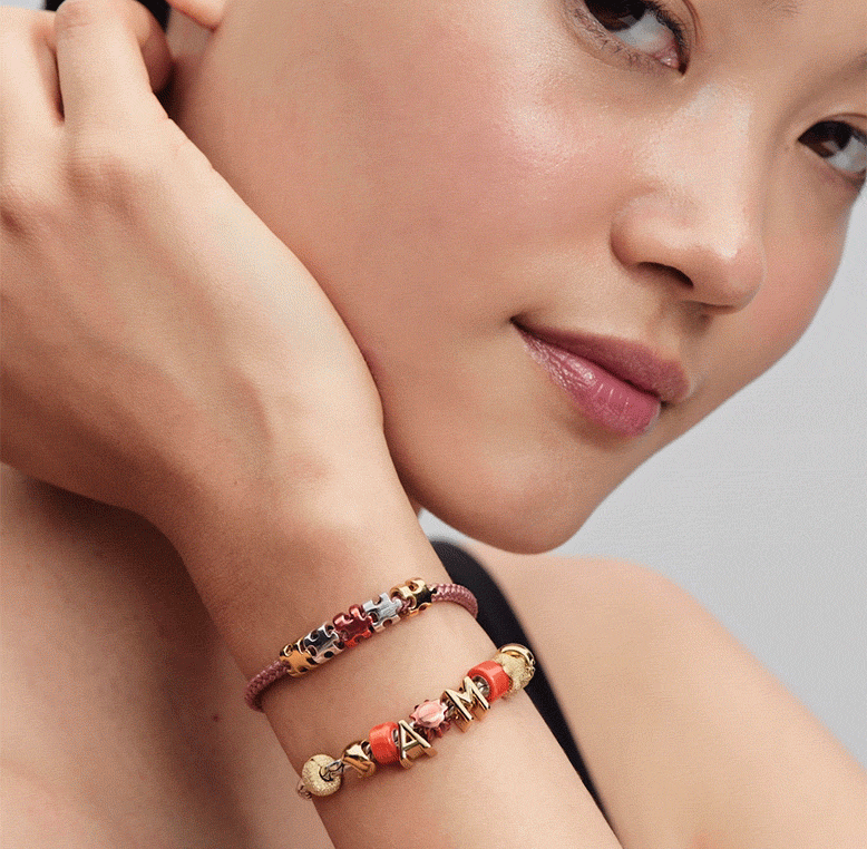 Model wears bracelet stack featuring silver, gold and orange minis