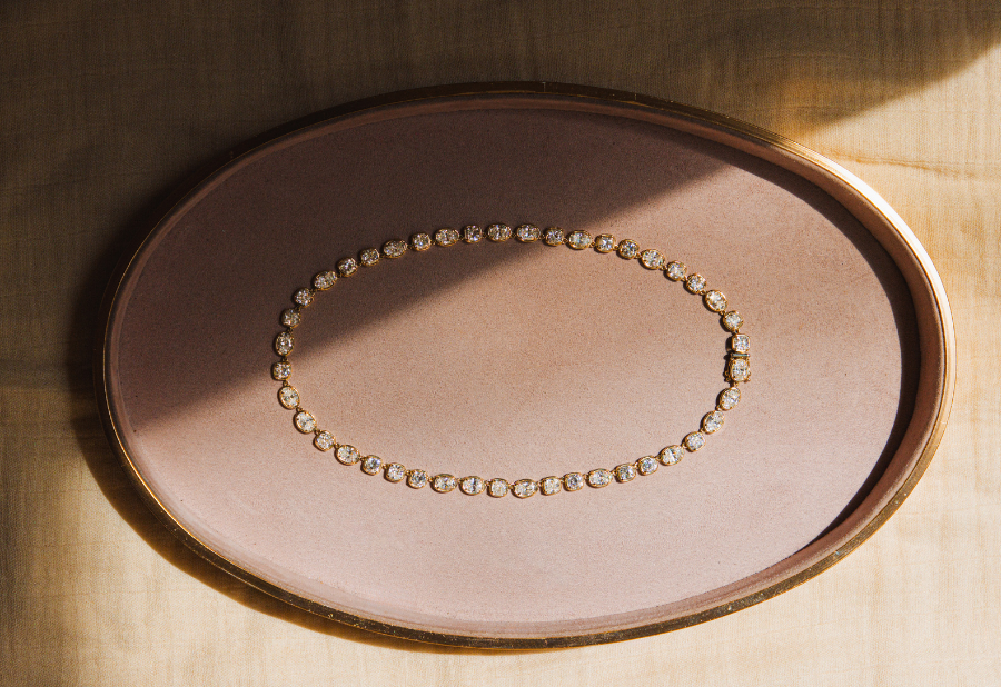 Flat lay of diamond necklace against a pink tray with pretty shadow light