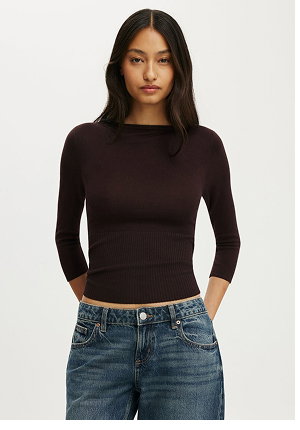 Woman wearing a dark brown ribbed long-sleeve top and blue jeans