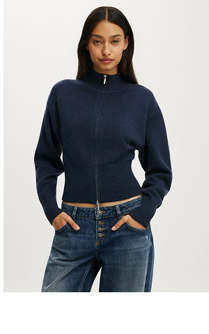 Woman wearing a dark navy cropped zip-up sweater and blue jeans