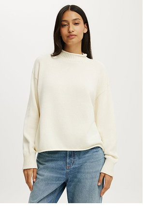 Woman wearing cream ribbed crew neck sweater with long sleeves styled with blue jeans