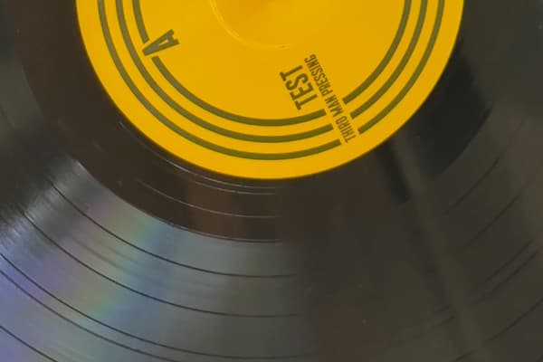 Close image of a vinyl record, with the Letter "A", and words "TEST, THRID MAN PRESSING", on a yellow sticker in the center.