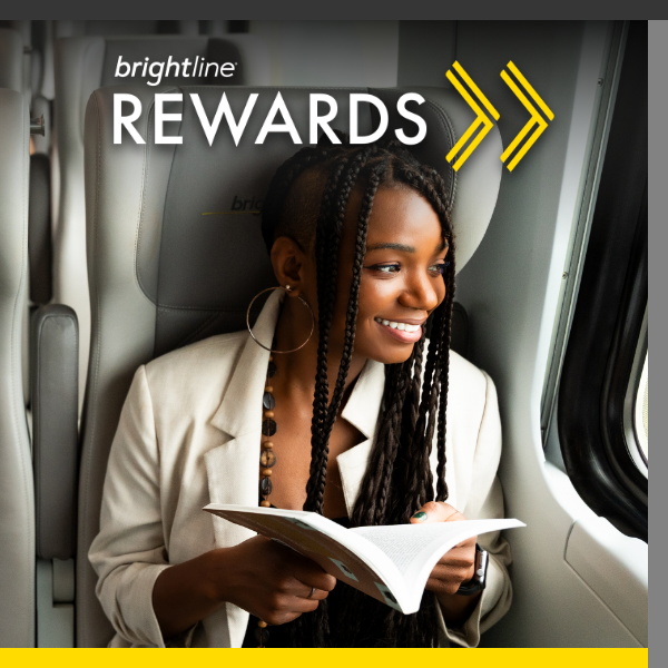 A young woman sits on a Brightline train, smiling while reading a book. The seat headrest behind her displays the Brightline name, and the top of the image features the text "brightline REWARDS" with yellow arrow graphics. She wears a light blazer and large hoop earrings, with natural light coming through the train window. The overall scene conveys a relaxed, modern travel experience associated with a rewards program.