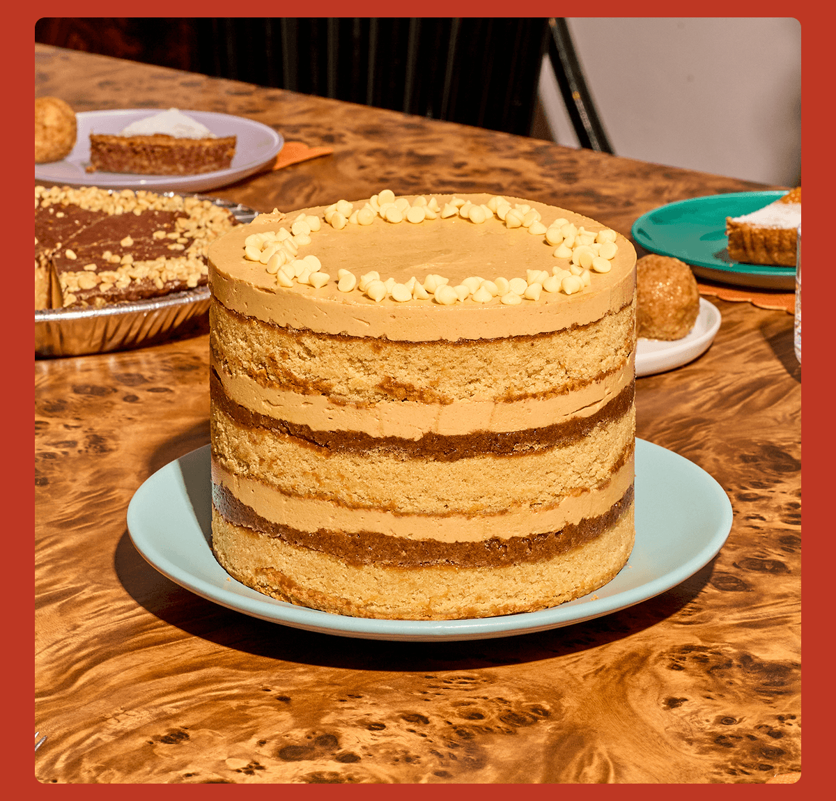 Maple Cookie Butter Cake with exposed layers of brown sugar cake, cookie butter frosting, and crunchy cookie butter, topped with cream-colored chips on a light blue plate.