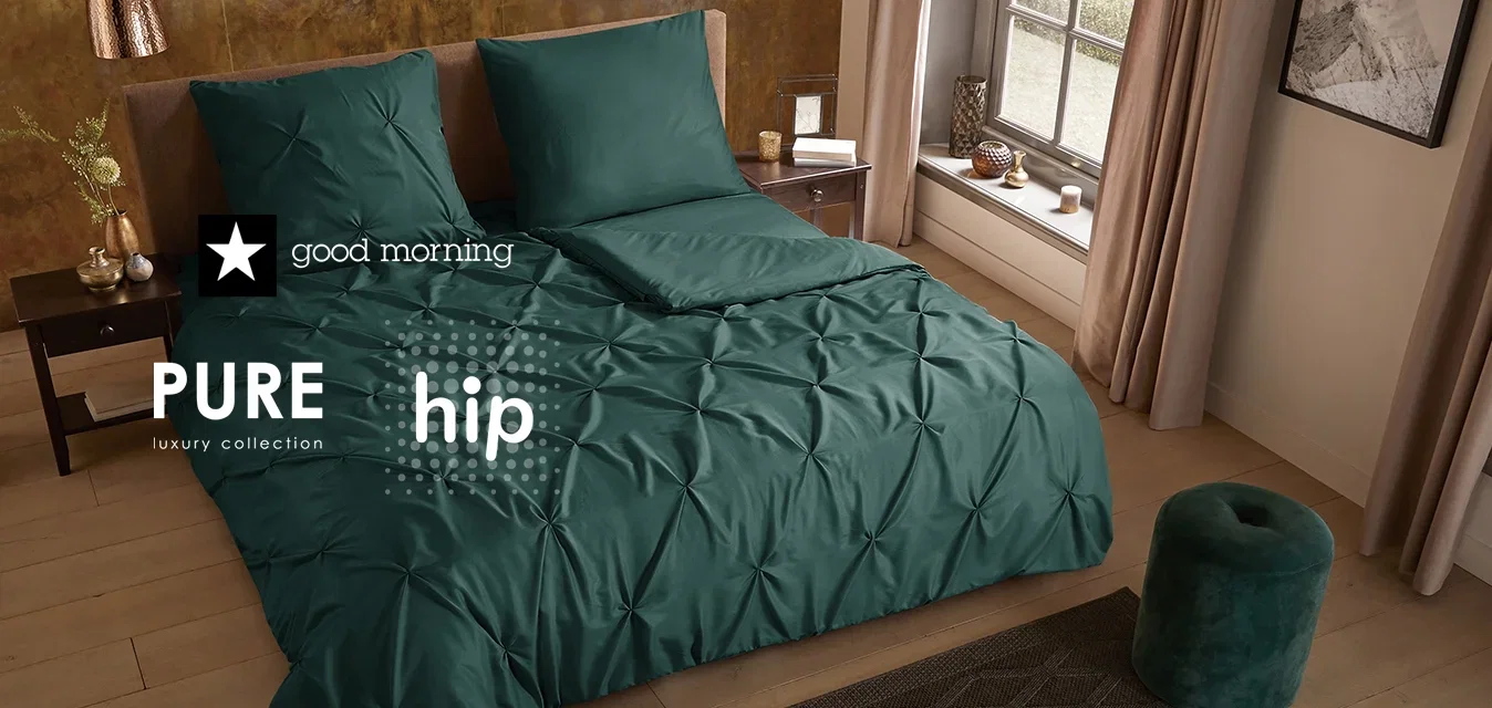Turkoois beddengoedset met getufte textuur, twee bijpassende kussens, een houten nachtkastje, een groene accentkruk en een donker patroon vloerkleed in een moderne kamer.