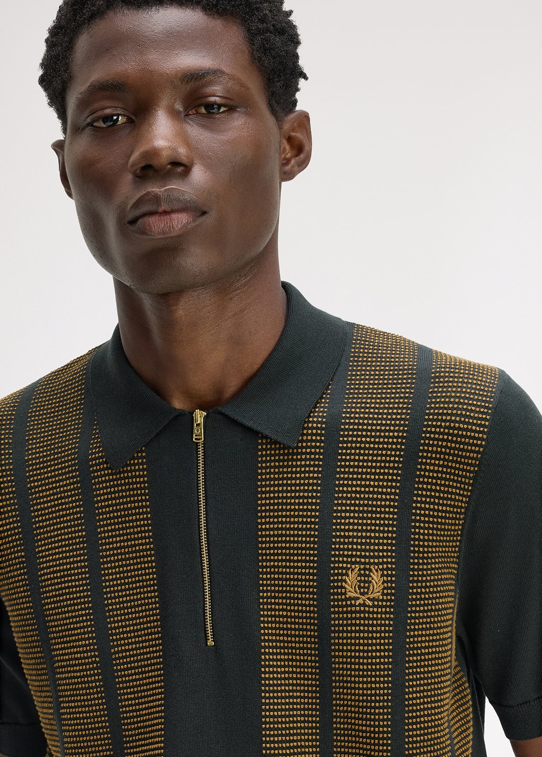 A male model wearing a Fred Perry Textured Panel Knitted Shirt in Night Green