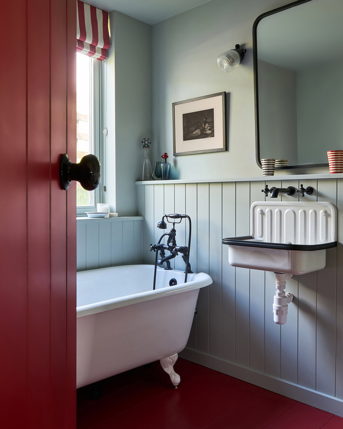 Bathroom featuring a Picture Gallery Red door contrasted with Light Blue walls, panelling and cabinetry.