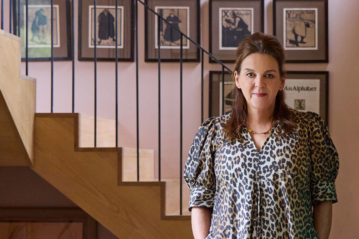 Farrow & Ball Colour Curator Joa Studholme standing in a warmly lit hallway beside a staircase.