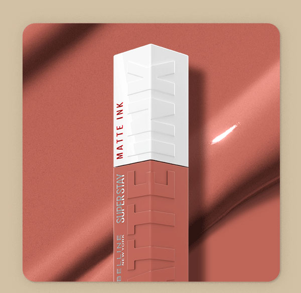Top of a Maybelline Super Stay Matte Ink Liquid Lipstick bottle in Seductress, a muted rose-nude shade, set against a soft rose satin backdrop with a swipe of glossy textured shade swatch.