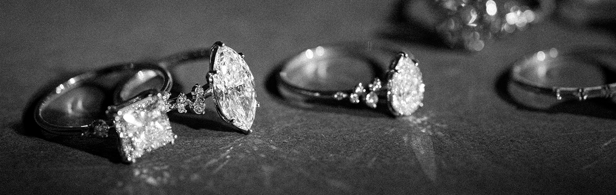 This image showcases a variety of Melanie Casey rings shown both in and out of focus places on a reflective surface.