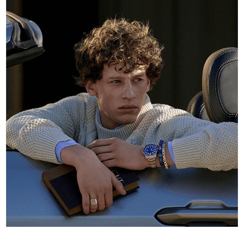 A model in a car wearing a variety of men’s jewelry pieces.