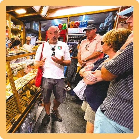 Image Description: Group food tour inside a bakery with the guide standing by the display case explaining something to the group.
