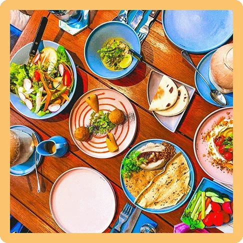 Image Description: Bird’s-eye view of a table showing multiple Mediterranean dishes with colorful and creative plating.