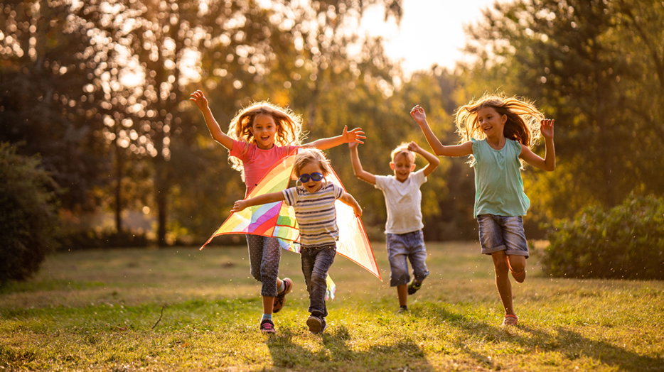 Kids running and flying a kite.