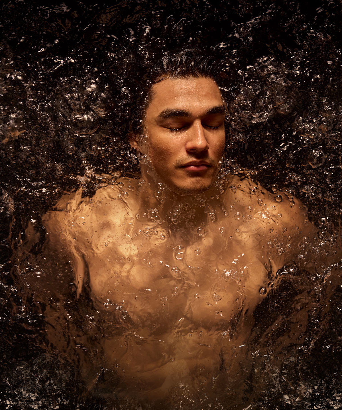 Person reclining in a warm bath with water surrounding the shoulders and neck.