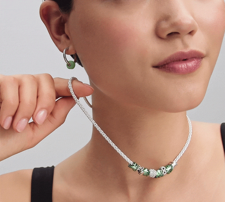 Model wears a necklace featuring green and silver minis