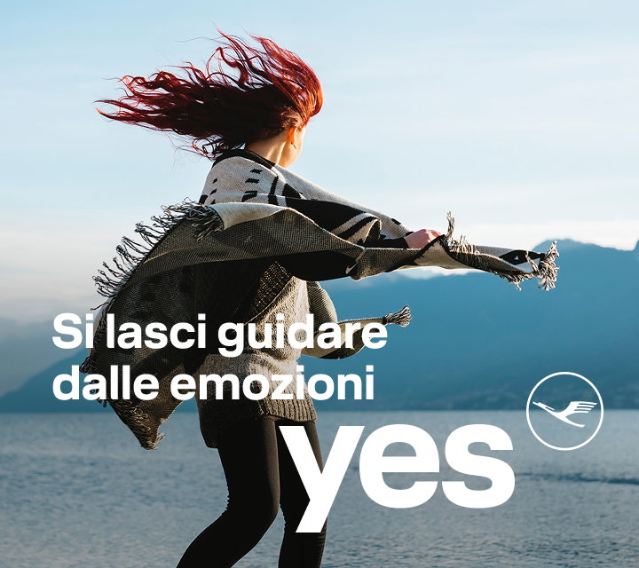 Persona sulla riva di un lago con una sciarpa che sventola