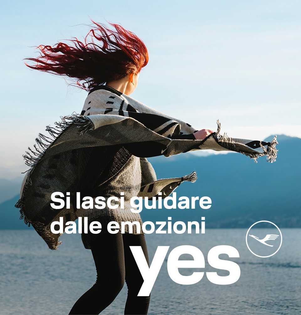 Persona sulla riva di un lago con una sciarpa che sventola