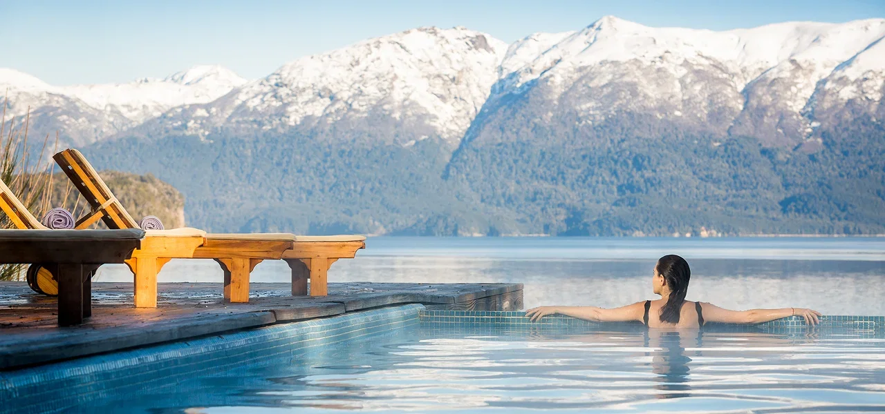 Guest relaxing in an infinity pool with mountain views.