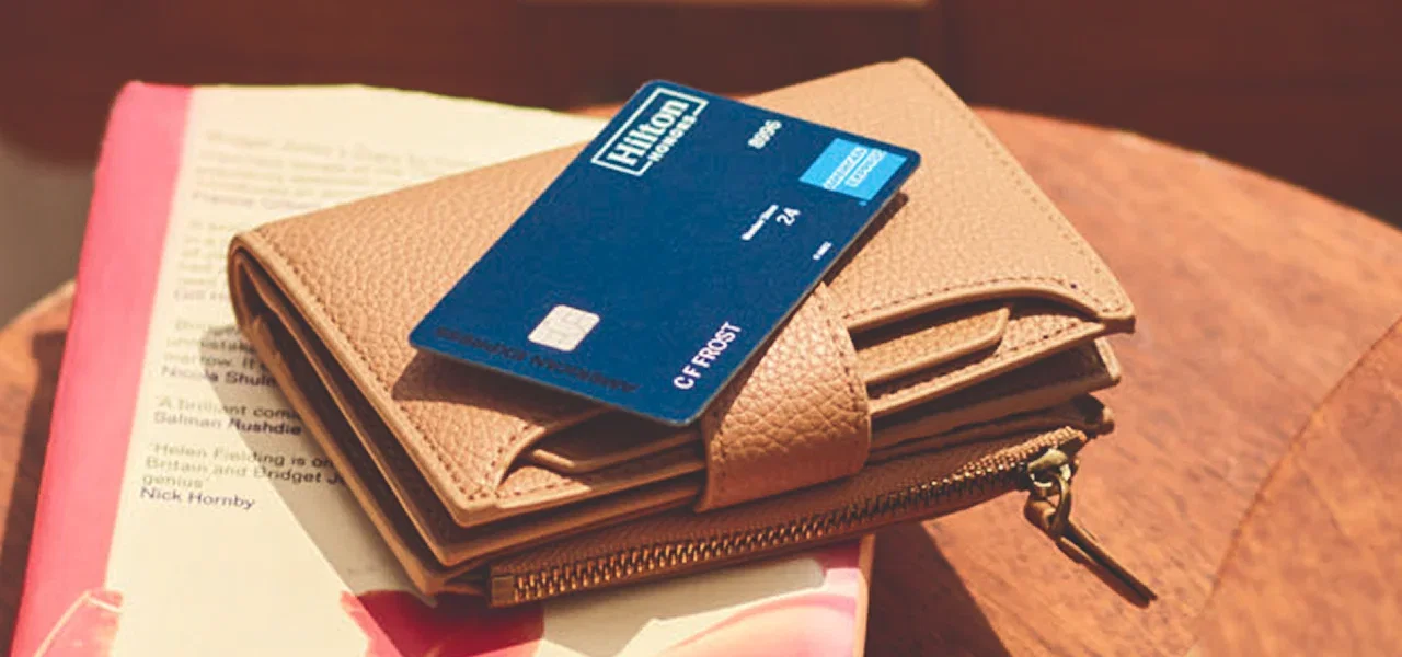 Hilton Honors Surpass Card on wallet atop a book.